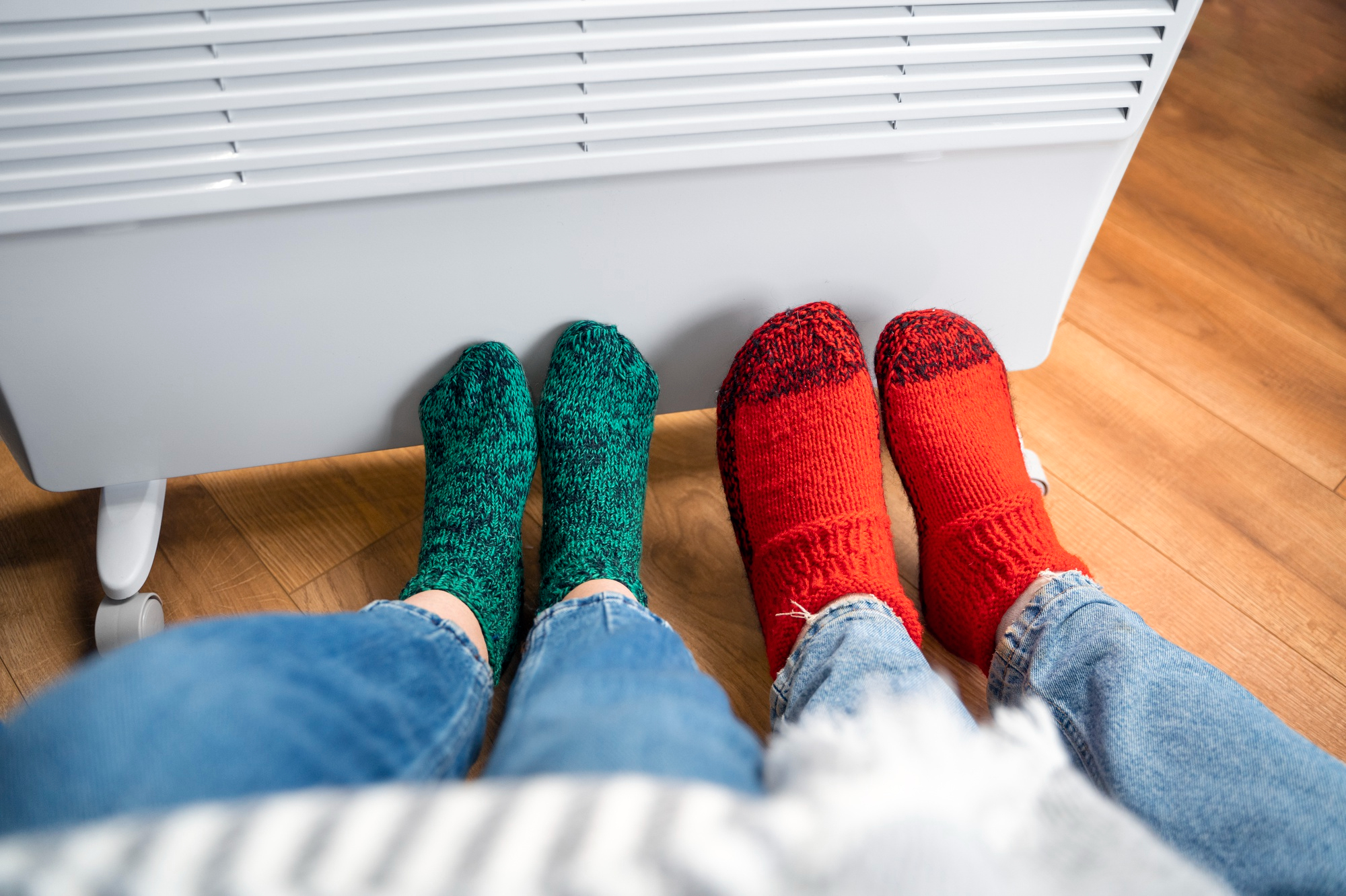 twee paar voeten in wollen sokken warmen zich aan een radiator