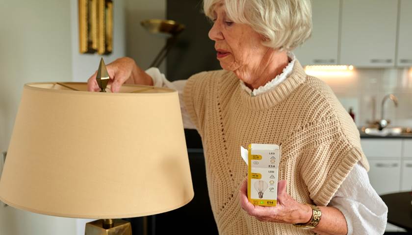 een vrouw installeert een ledlamp in een staande lamp