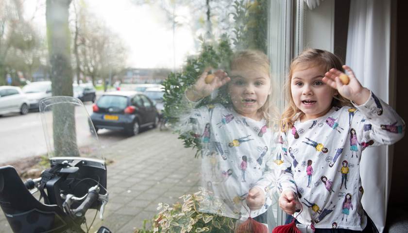 een jong kind zwaait door een raam